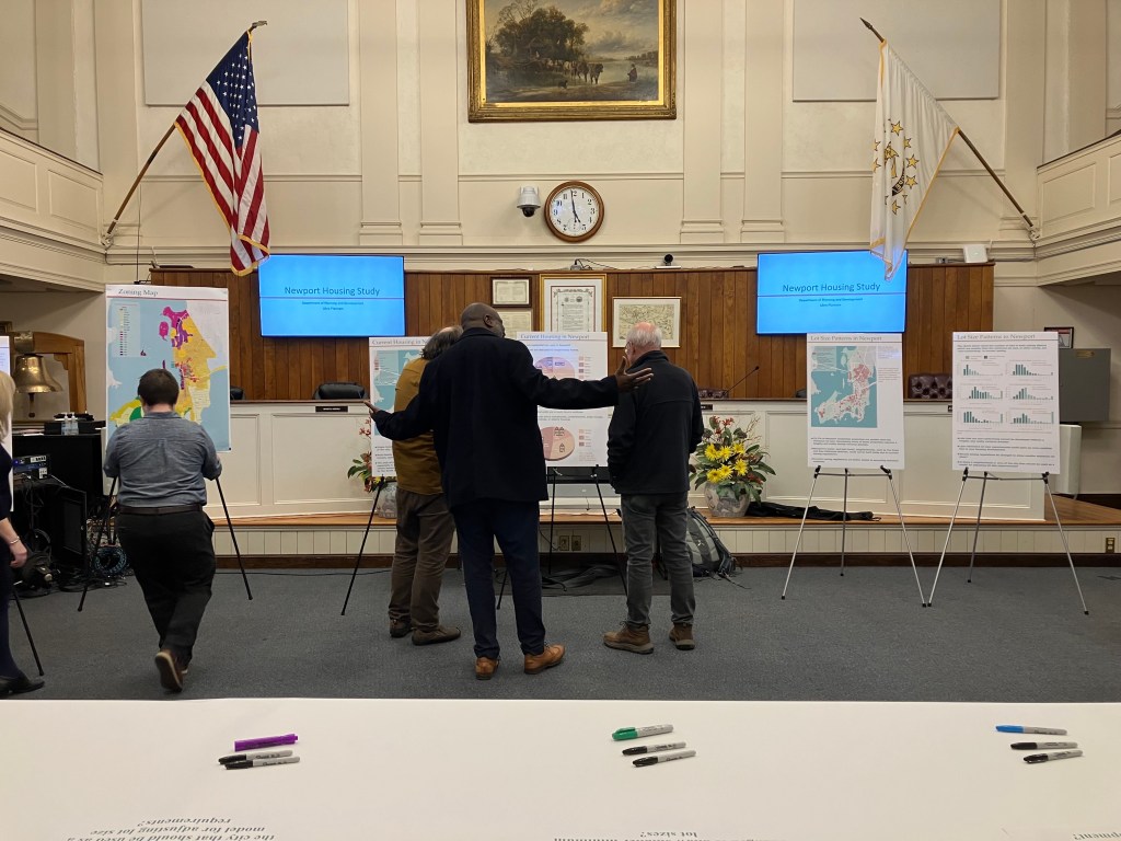 Just before the start of an open house meeting, a city worker adjusts one of the displays that illustrate results from a new study about Newport’s housing stock as attendees view the data on the displays on Thursday night, Feb. 22, 2024.