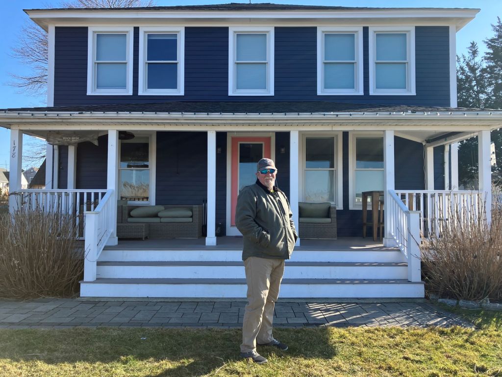 Common Fence Point resident Tom Charbonneau stands for a portrait in front of his family home, just a few feet above sea level and facing Mount Hope Bay, on Friday, March 4, 2024.