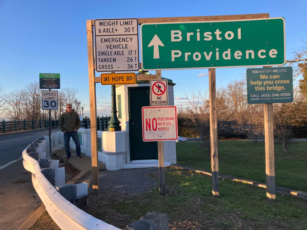 Bryan Ganley stands at the Portsmouth entrance to the Mount Hope Bridge surrounded by signs on Friday, Jan. 5, 2024.