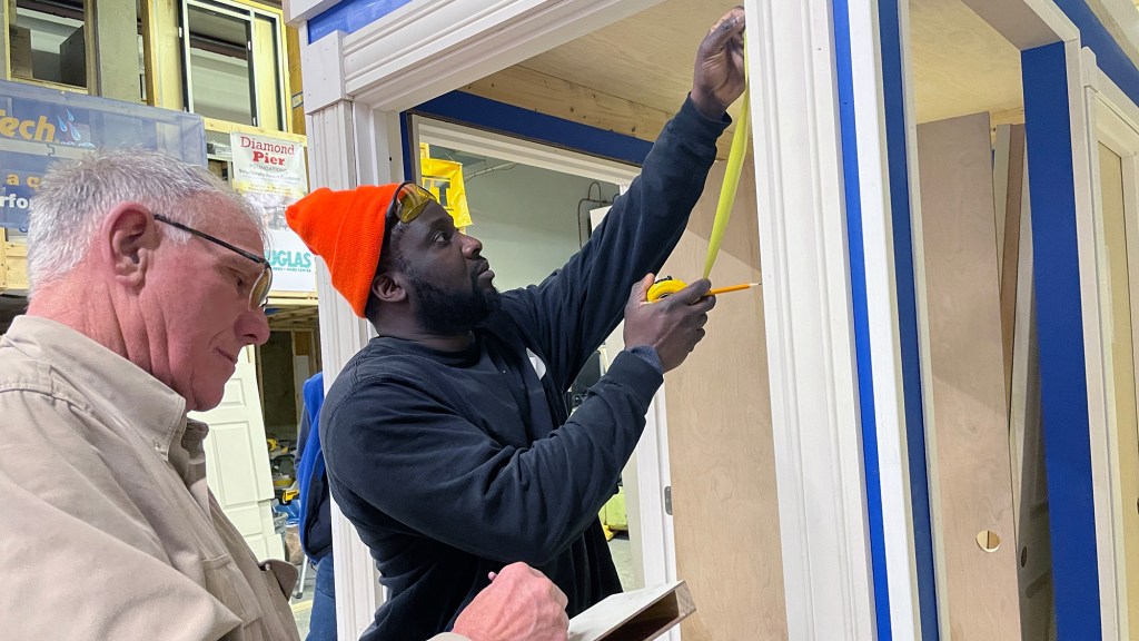 Jide Williams takes measurements of a door frame in a training class coordinated through Rhode Island Housing.